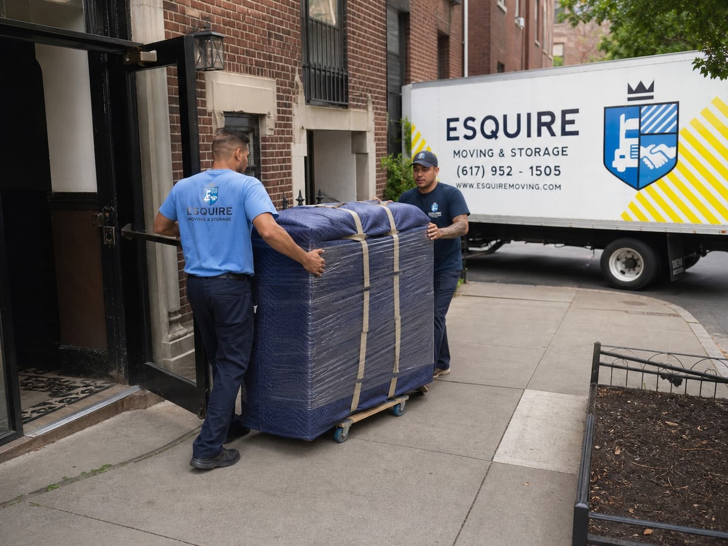Esquire movers guiding a protected dresser from a New York apartment building toward a branded truck