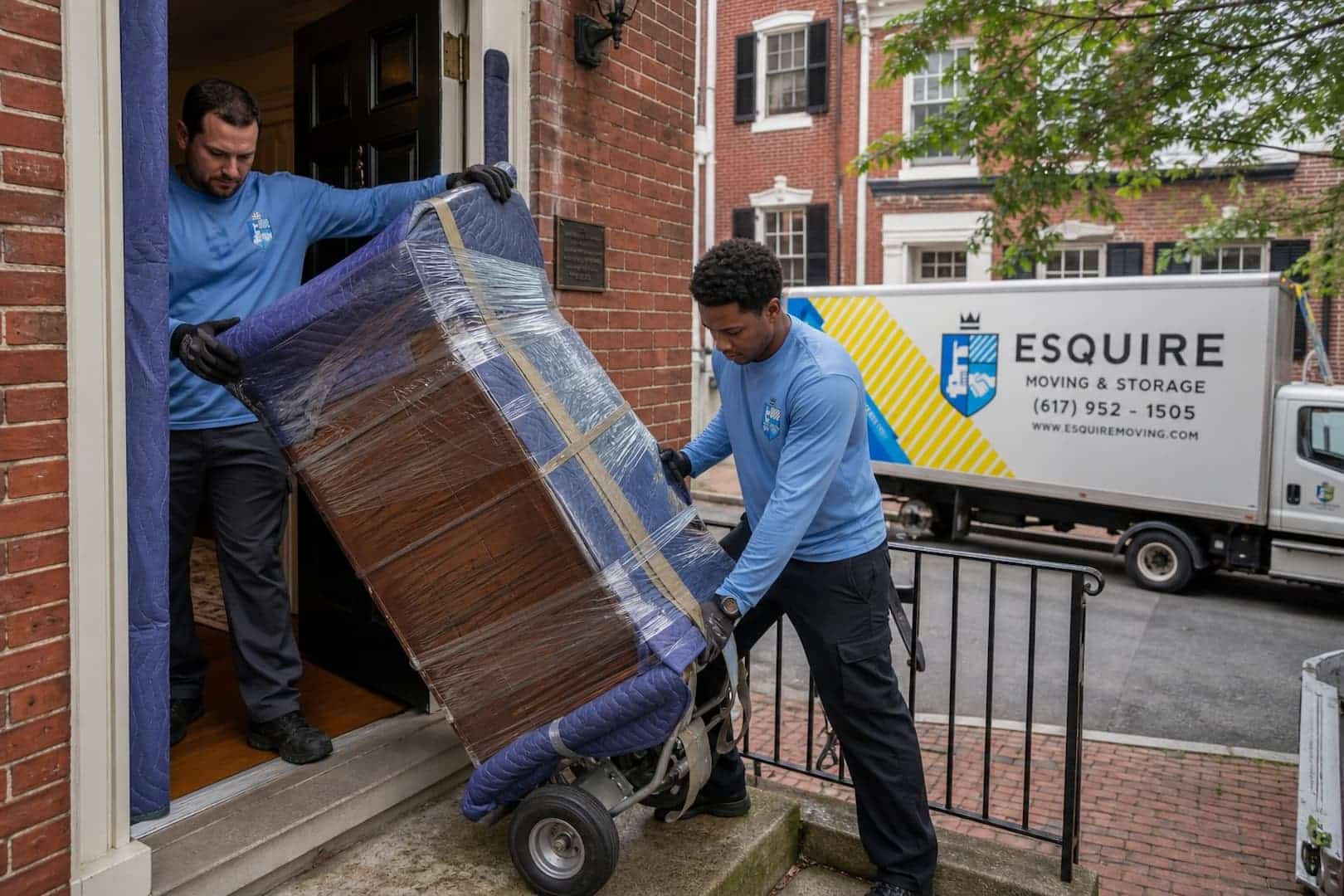 Esquire movers carrying a wrapped dresser through a doorway in Old Town Alexandria