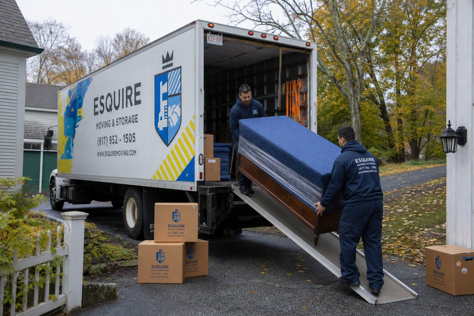 Esquire movers loading a padded dresser into a branded truck at a Vermont home